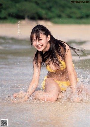 A woman in a bikini sitting on a grassy field.