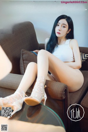 A woman sitting on a couch with her legs crossed.