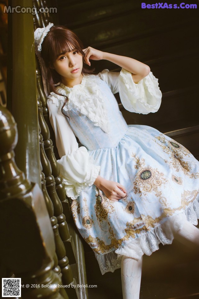 A woman in a blue and white dress sitting on a staircase.