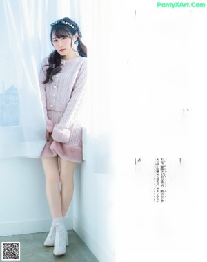 A woman in a pink sweater sitting on a wooden table.