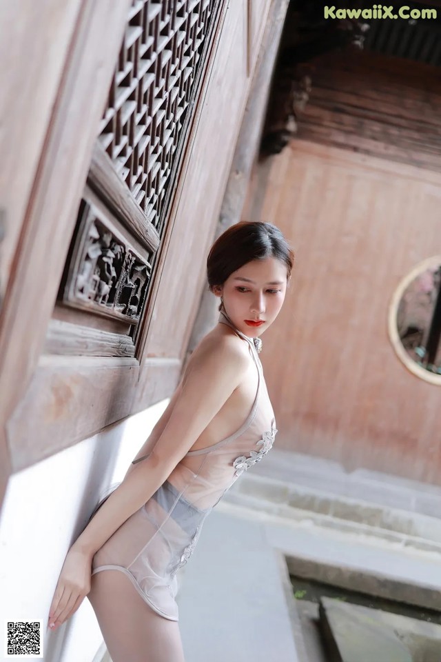 A woman in a white lingerie leaning against a wall.