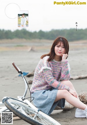 A woman riding a bike on a beach next to the ocean.