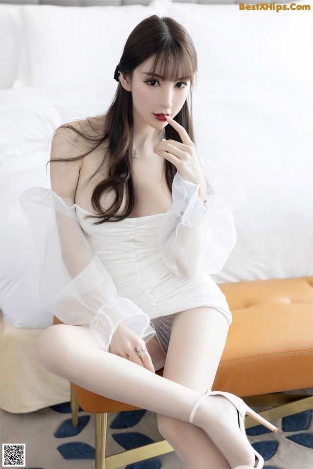 a woman in a white dress sitting on a chair