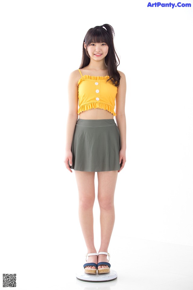 A woman in a yellow top and a green skirt.