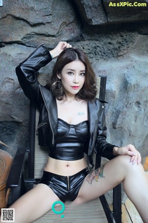 A woman in a black leather jacket and shorts posing for a picture.