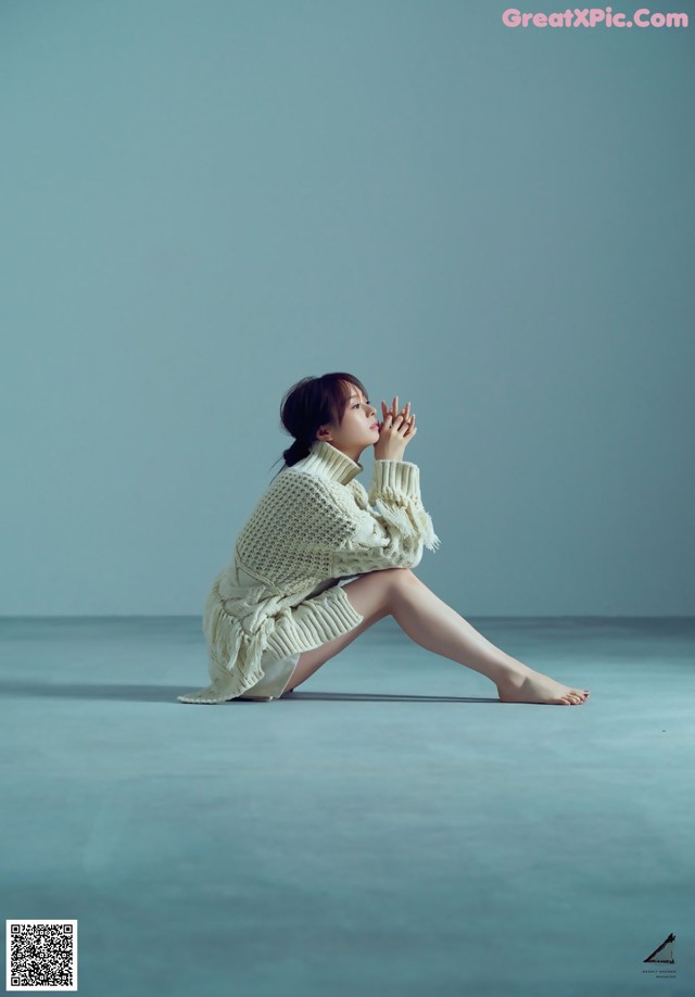 A woman sitting on the ground with her legs crossed.