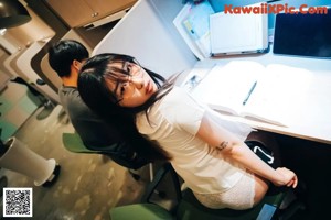 A woman sitting at a desk with a tattoo on her arm.