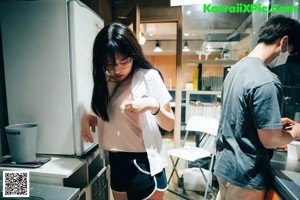 A woman sitting on top of a stool in a kitchen.